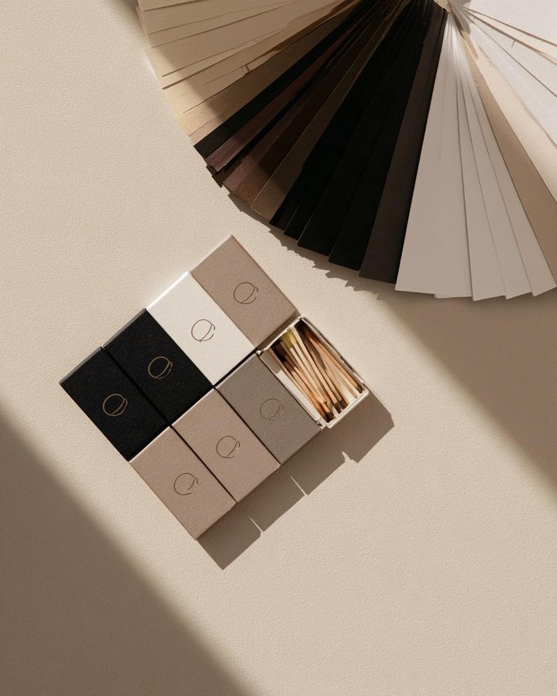 Black, white and stone monogram matchboxes beside a fan of colour swatches