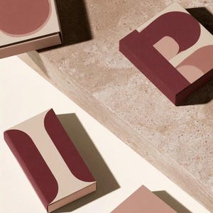 Contemporary matchbox mockup with a coloured paper sleeve and a clean graphic layout. The rectangular box is presented in soft directional light as a personalised wedding or event favour concept.