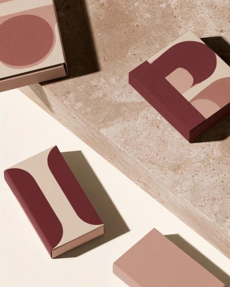 Contemporary matchbox mockup with a coloured paper sleeve and a clean graphic layout. The rectangular box is presented in soft directional light as a personalised wedding or event favour concept.