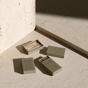 Cream rectangular drawer-style matchbox mockups arranged with coordinating neutral paper samples. The presentation shows sleeves, trays and the compact box proportions for bespoke event designs.