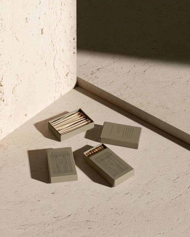 Cream rectangular drawer-style matchbox mockups arranged with coordinating neutral paper samples. The presentation shows sleeves, trays and the compact box proportions for bespoke event designs.