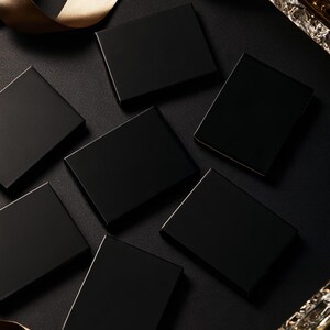 Dark matchbox mockups styled for an evening celebration, with plain and gold-toned decorative sleeve designs. The presentation shows compact rectangular boxes for personalised party favours.