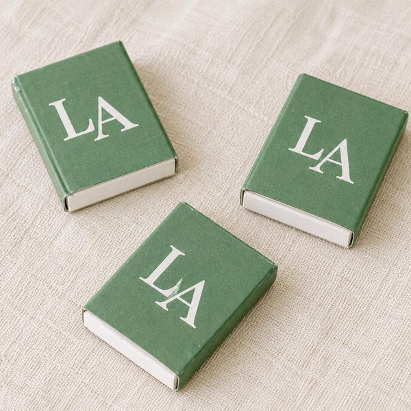 Green matchboxes printed with a large white LA monogram