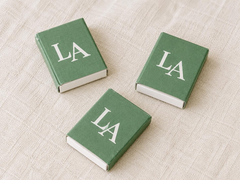 Green matchboxes printed with a large white LA monogram