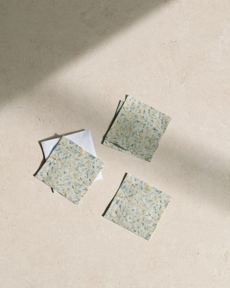 Square cocktail-napkin and paper-detail mockups with fine botanical line illustrations, styled with coordinating paper pieces. Digital presentation of a custom illustrated wedding and event design.