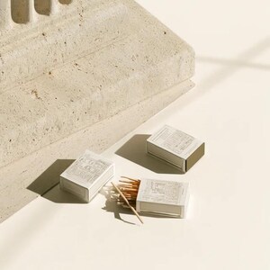 Cream rectangular drawer-style matchbox mockups arranged with coordinating neutral paper samples. The presentation shows sleeves, trays and the compact box proportions for bespoke event designs.