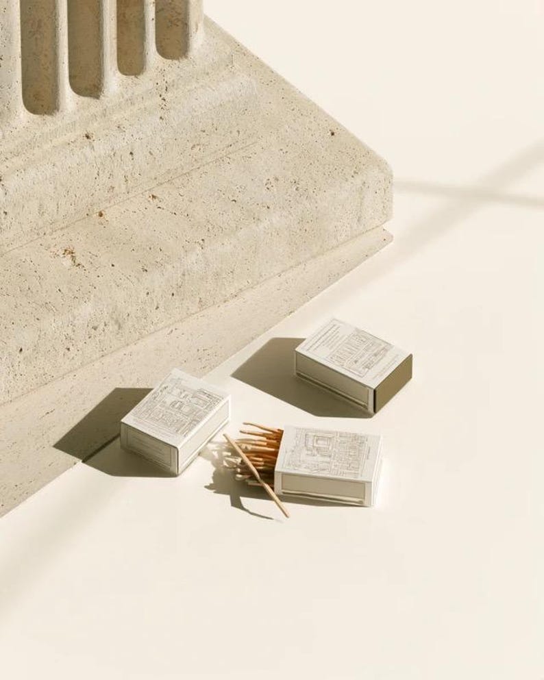 Cream rectangular drawer-style matchbox mockups arranged with coordinating neutral paper samples. The presentation shows sleeves, trays and the compact box proportions for bespoke event designs.