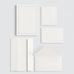 Unprinted cream invitation cards in several rectangular sizes with matching envelopes, arranged on a pale background. The mockup shows a coordinated wedding invitation, reply card and details-card format.