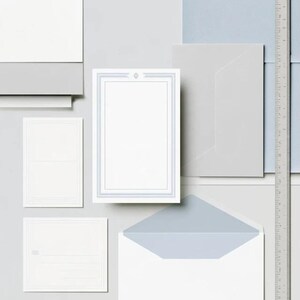 Unprinted cream invitation cards in several rectangular sizes with matching envelopes, arranged on a pale background. The mockup shows a coordinated wedding invitation, reply card and details-card format.