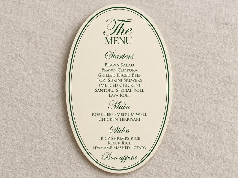Może przedstawiać: Owalna karta menu w kolorze kremowym z ciemnozielonymi liniami brzegowymi i ciemnozielonym tekstem. Menu zawiera sekcje Starters, Main i Sides, w tym dania takie jak Prawn Salad, Grilled Diced Beef, Kobe Beef i Edamame Mashed Potato, kończąc się Bon appetit.