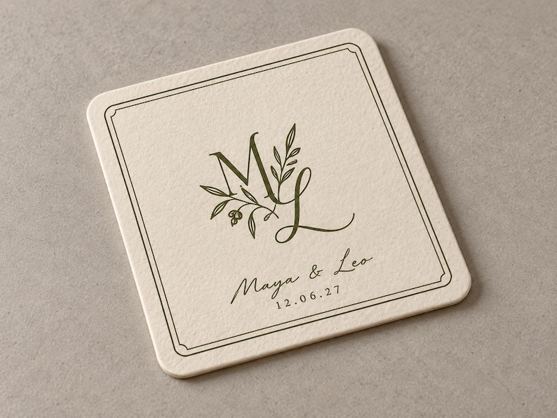 Digital close-up mockup of a square ivory paper coaster with rounded corners, olive ML monogram, fine double-line frame and personalised wording on a plain warm-grey surface, showing the paper texture.