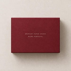 AI-assisted studio illustration of the reverse of the burgundy 14.5 cm matchbox, with ivory sample wording: Bespoke Paper Goods, Made Personal.