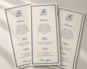 May include: Three tall, cream-colored restaurant menus with dark blue borders and elegant blue text. The menus feature sections for Starters, Main, and Sides, listing items like Prawn Salad, Grilled Diced Beef, and Chicken Teriyaki, ending with Bon appetit.