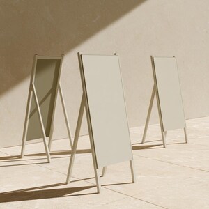 A tall cream wedding-sign mockup displayed upright with coordinated cream and olive paper stationery on a neutral surface. Soft daylight highlights the simple rectangular layout and paper textures.