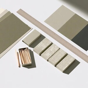 Cream rectangular drawer-style matchbox mockups arranged with coordinating neutral paper samples. The presentation shows sleeves, trays and the compact box proportions for bespoke event designs.