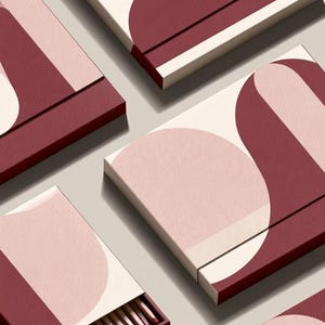 Contemporary matchbox mockup with a coloured paper sleeve and a clean graphic layout. The rectangular box is presented in soft directional light as a personalised wedding or event favour concept.