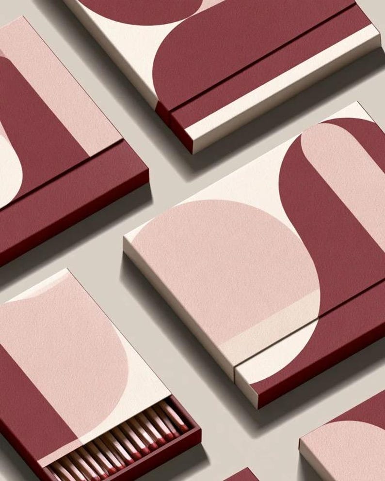 Contemporary matchbox mockup with a coloured paper sleeve and a clean graphic layout. The rectangular box is presented in soft directional light as a personalised wedding or event favour concept.