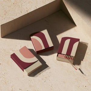Contemporary matchbox mockup with a coloured paper sleeve and a clean graphic layout. The rectangular box is presented in soft directional light as a personalised wedding or event favour concept.