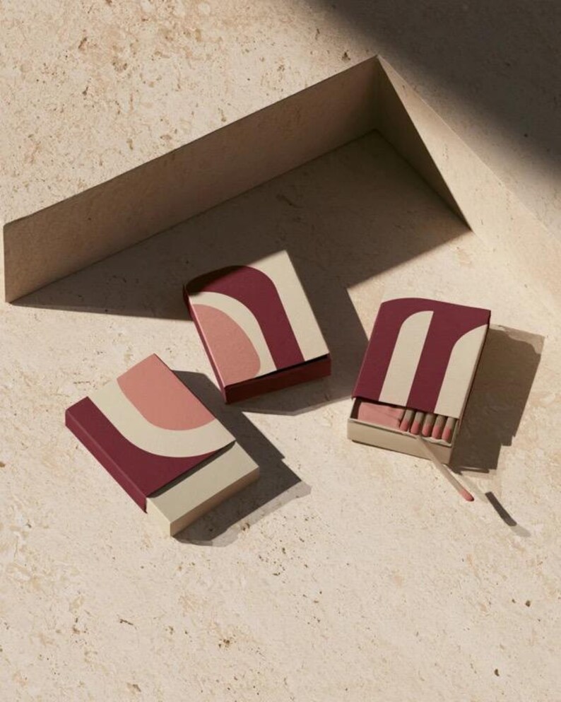 Contemporary matchbox mockup with a coloured paper sleeve and a clean graphic layout. The rectangular box is presented in soft directional light as a personalised wedding or event favour concept.