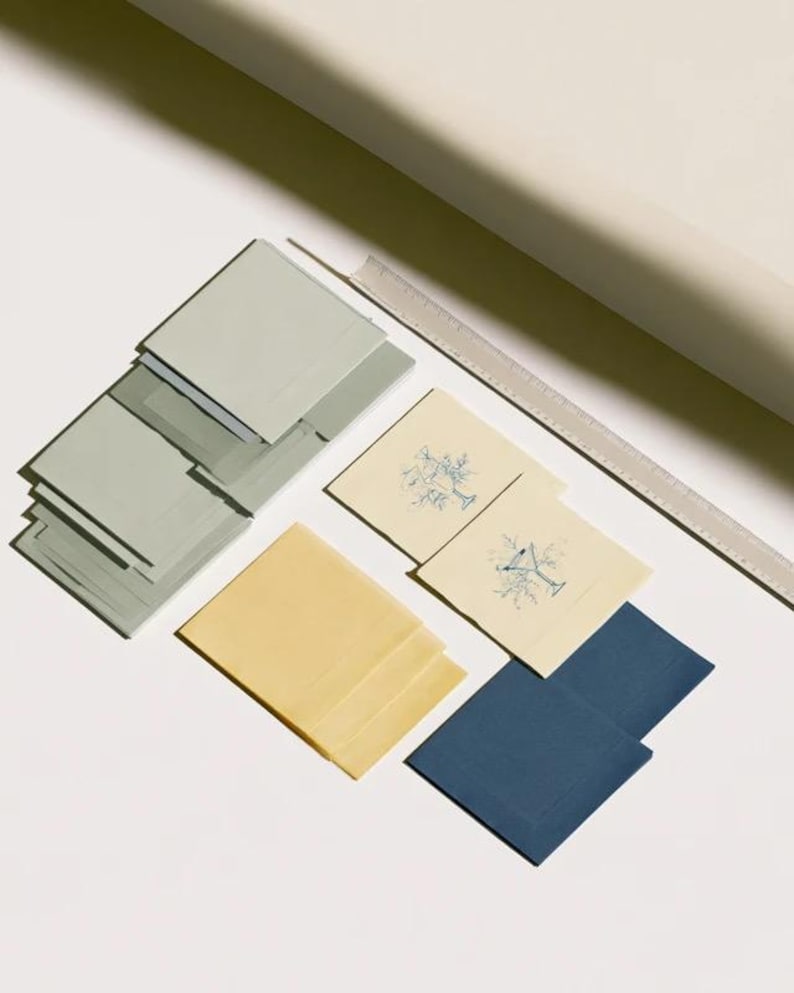 Square cocktail-napkin and paper-detail mockups with fine botanical line illustrations, styled with coordinating paper pieces. Digital presentation of a custom illustrated wedding and event design.