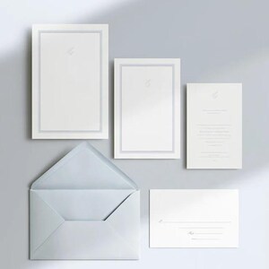 Unprinted cream invitation cards in several rectangular sizes with matching envelopes, arranged on a pale background. The mockup shows a coordinated wedding invitation, reply card and details-card format.