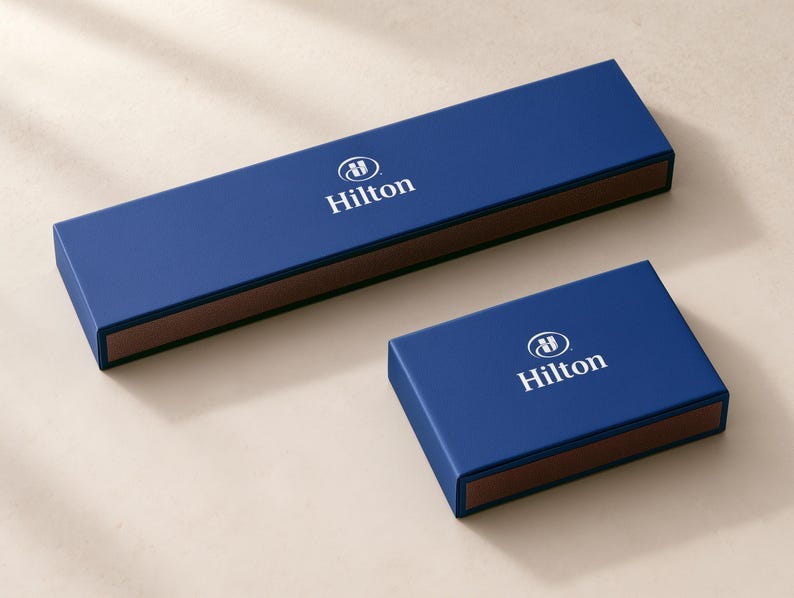Concept mockup of blue matchboxes in 28cm and 14.5cm formats, featuring white Hilton branding.