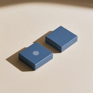Contemporary matchbox mockup with a coloured paper sleeve and a clean graphic layout. The rectangular box is presented in soft directional light as a personalised wedding or event favour concept.