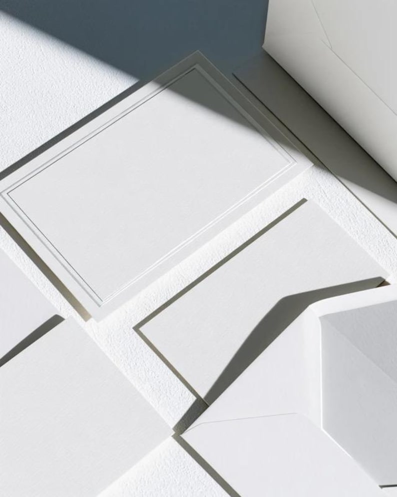 Unprinted cream invitation cards in several rectangular sizes with matching envelopes, arranged on a pale background. The mockup shows a coordinated wedding invitation, reply card and details-card format.