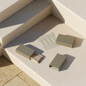 Cream rectangular drawer-style matchbox mockups arranged with coordinating neutral paper samples. The presentation shows sleeves, trays and the compact box proportions for bespoke event designs.