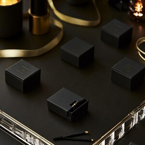 Dark matchbox mockups styled for an evening celebration, with plain and gold-toned decorative sleeve designs. The presentation shows compact rectangular boxes for personalised party favours.