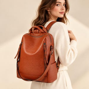 May include: A rust-coloured backpack with a textured surface, featuring a top handle, adjustable shoulder straps, and two vertical zippered front pockets with long pull tabs. The bag includes side pockets and dark metal hardware accents.