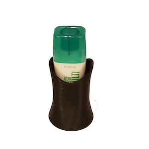 Peut inclure: Un support de bouteille de colle marron foncé en forme de sablier, contenant une bouteille de colle à bouchon vert. La bouteille porte des étiquettes blanches et vertes avec le texte "MULTI GLUE". Le support est conçu pour maintenir la bouteille de colle en position verticale.