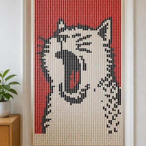 May include: A beaded doorway curtain featuring a pixelated graphic of a yawning cat. The design is composed of small, round beads in white, black, and red, creating a stylized feline face against a solid red background within a rectangular frame.