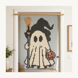 May include: A beaded door curtain featuring a pixelated design of a ghost wearing a black witch hat, holding a tan broomstick and an orange jack-o'-lantern. The curtain is composed of numerous small, light-colored beads suspended from a wooden rod.
