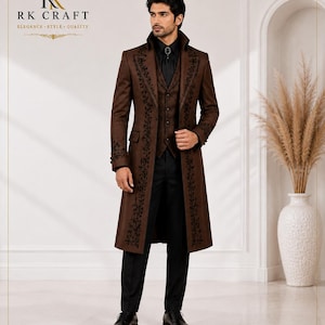 May include: A brown long coat featuring black floral embroidery along the lapels and cuffs, worn over a matching brown vest, a black shirt with a dark neck accessory, and black trousers. The RK CRAFT logo is visible in the top left corner.