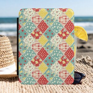 Op de afbeelding: Een rechthoekige tablethoes met een ruitvormig quiltpatroon. Het ontwerp bestaat uit afwisselende vierkanten in rood gingham, geel met witte stippen en blauwgroen met kleine bloemenprints en piepkleine rode hartjes over het hele oppervlak.