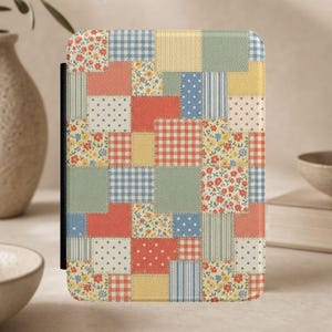 May include: A rectangular e-reader cover featuring a patchwork design of various fabric patterns including red and white gingham, blue and white polka dots, small floral prints, solid yellow, and sage green squares with visible stitched edges.
