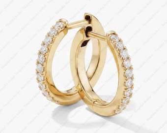 Peut inclure: Une paire de créoles en or ornée d'une rangée de petites pierres claires taille ronde serties sur le bord extérieur avant de chaque anneau. Les boucles d'oreilles présentent une finition métallique polie et un fermoir à charnière.