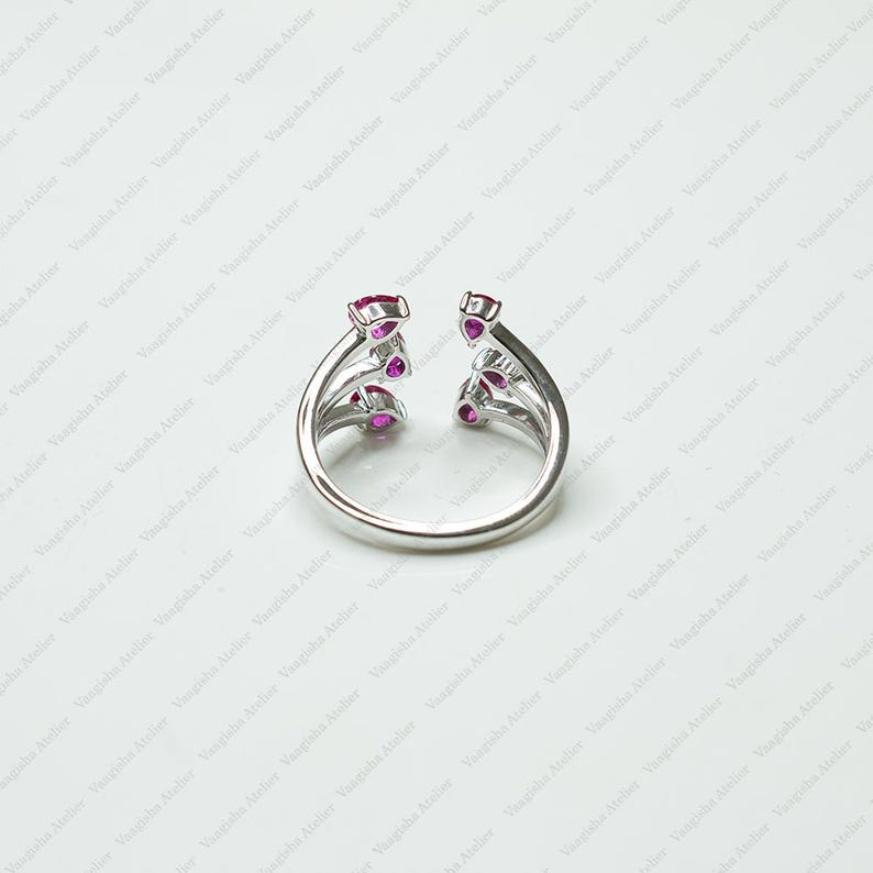 Peut inclure: Une bague ouverte argent&eacute;e orn&eacute;e de trois pierres rose fonc&eacute; en forme de poire de chaque c&ocirc;t&eacute;. L'anneau est lisse et poli, avec les pierres dispos&eacute;es verticalement le long des deux extr&eacute;mit&eacute;s du design ouvert, cr&eacute;ant un aspect sym&eacute;trique.