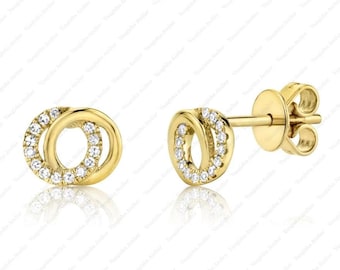 Peut inclure: Une paire de boucles d'oreilles à tige en or avec un motif de deux cercles entrelacés. Un cercle est en or poli, tandis que l'autre est serti de petites pierres rondes transparentes. Les boucles d'oreilles sont dotées de fermoirs à tige.