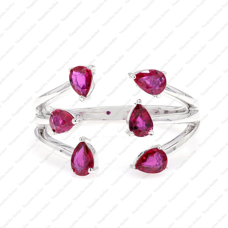 Peut inclure: Une bague ouverte argent&eacute;e orn&eacute;e de six pierres pr&eacute;cieuses rose vif taill&eacute;es en poire, dispos&eacute;es dans un style bypass. L'anneau se divise en plusieurs brins, chacun se terminant par une pierre rose en forme de goutte d'eau.