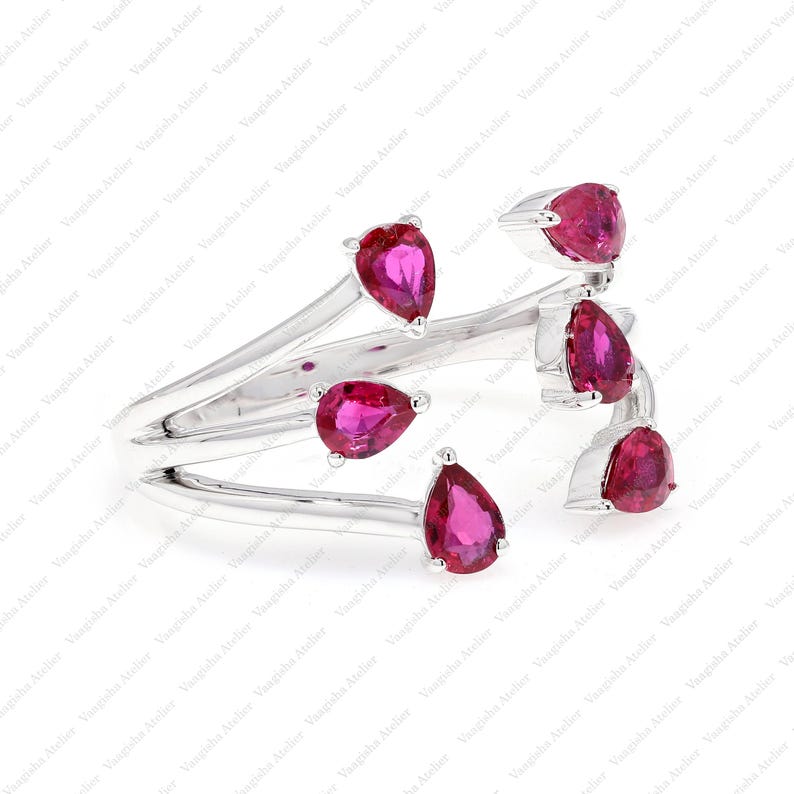 Peut inclure: Une bague ouverte argent&eacute;e orn&eacute;e de cinq pierres pr&eacute;cieuses rose vif en forme de poire, dispos&eacute;es dans un style bypass. L'anneau se divise en plusieurs branches en m&eacute;tal poli, chacune se terminant par une pierre en goutte d'eau.