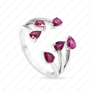 Peut inclure: Une bague ouverte en argent orn&eacute;e de cinq pierres pr&eacute;cieuses taille poire d'un rouge ros&eacute; profond. L'anneau se divise en plusieurs griffes, chacune portant une pierre en forme de goutte &agrave; l'extr&eacute;mit&eacute;, cr&eacute;ant un design asym&eacute;trique poli.