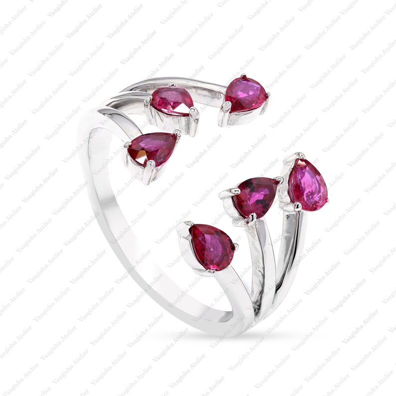 Peut inclure: Une bague ouverte en argent orn&eacute;e de cinq pierres pr&eacute;cieuses taille poire d'un rouge ros&eacute; profond. L'anneau se divise en plusieurs griffes, chacune portant une pierre en forme de goutte &agrave; l'extr&eacute;mit&eacute;, cr&eacute;ant un design asym&eacute;trique poli.