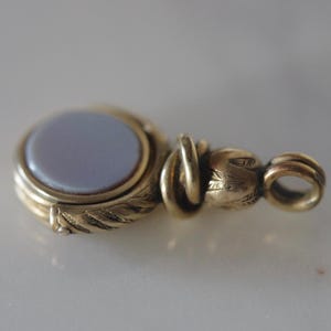 May include: A gold-toned fob seal with a light blue cameo set in a decorative frame. The seal has a loop for attaching to a chain.