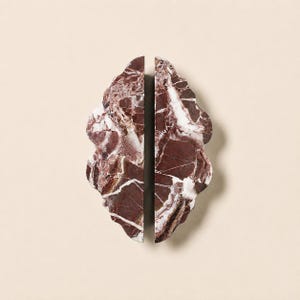 May include: A pair of bookends crafted from deep burgundy marble with prominent white veining. Each piece features a scalloped, organic edge profile and a flat vertical side, showcasing the natural stone texture and polished finish of the material.