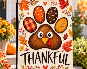 May include: A rectangular garden flag featuring a central brown turkey paw print design with a turkey face, surrounded by autumn leaves, berries, and hearts. The word THANKFUL is printed in large black letters at the bottom of the flag.