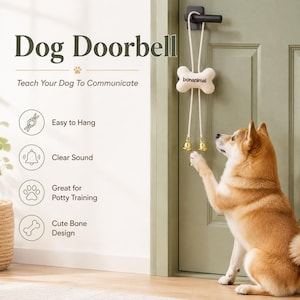 Peut inclure: Une sonnette pour chien suspendue à une poignée de porte noire, composée d'une pièce en forme d'os crème avec le texte bonanimal imprimé, fixée à une corde blanche avec deux clochettes en métal doré suspendues pour la communication animale.
