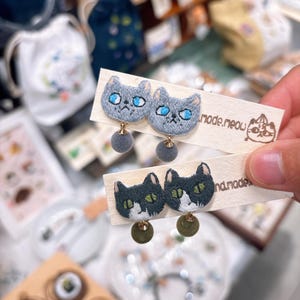 手刺繍の猫の顔のぶら下がりピアス（ポンポン付き）、個性的な子猫ジュエリー