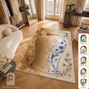 Puede incluir: Una alfombra rectangular con un gran diseño de jarrón central. El lado izquierdo del jarrón tiene un acabado texturizado y desgastado en tonos beige y marrón, mientras que el lado derecho muestra intrincados patrones florales azules sobre fondo crema.